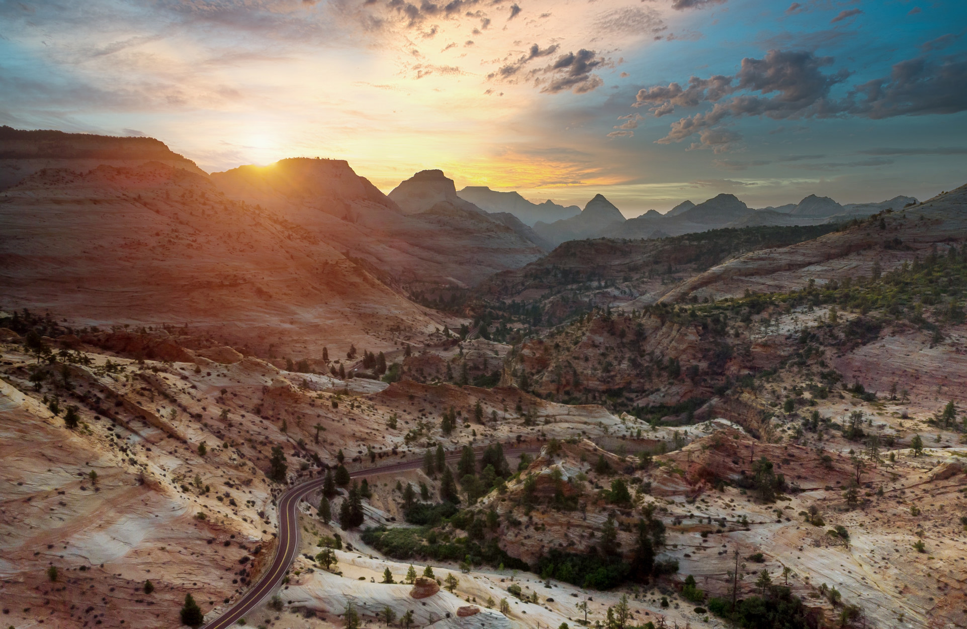 A two-lane road into Utah sandstone at sunset.